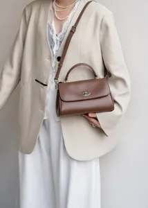 Braune Leder-Umhängetasche Detail, stilvoller Metall-Drehverschluss für elegante Frühlingsoutfits.