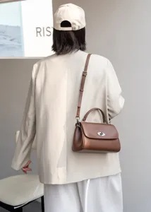 Detailansicht einer braunen Leder Umhängetasche, getragen von einem Modell im schicken Stil.