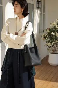Black genuine leather bucket bag detail, soft pebbled texture, casual chic daily commuter style.