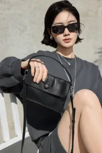 Chic black genuine leather top-handle bag featuring minimalist flap design and button closure.