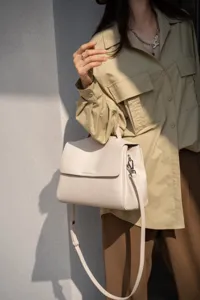 Detail view of the soft cowhide beige handbag, featuring elegant flap closure and strap.