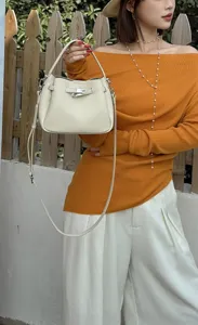 Mini leather bucket bag with metal lock detail, stylish crossbody handbag for women daily wear.