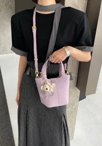 Detailed view of a chic light purple leather bucket bag with cute bear charm and strap.