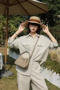 Detailed view of the mini leather top-handle crossbody bag worn in an outdoor garden scene.
