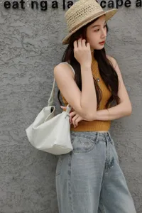 Dettaglio della borsa hobo morbida in pelle bianca indossata dalla modella, stile casual.