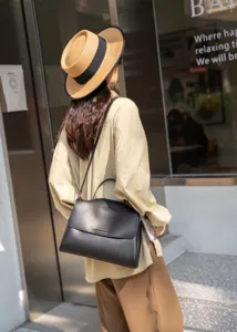 Detail shot of the black leather shoulder bag worn on model, showcasing the sleek design and strap.