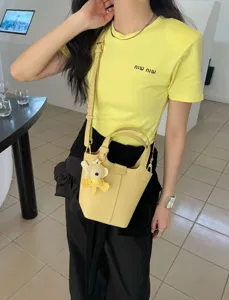 Genuine leather bucket bag with cute bear charm, stylish yellow handbag for women detail.