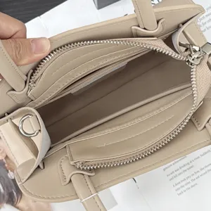 Detail view of beige leather women handbag, showing spacious interior compartments and smooth zippers.