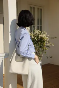 Detailed lifestyle view of minimalist leather bucket shoulder bag in casual daily styling.