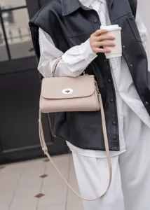 Elegante beige Umhängetasche aus Leder mit Metall-Drehverschluss und feinem verstellbaren Gurt.