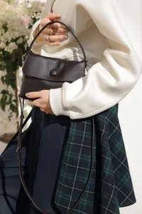 Close-up detail of the genuine leather button handbag, showing texture and handle design.