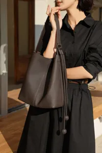 Detail view of dark brown genuine leather bucket bag with stylish knot drawstring design.