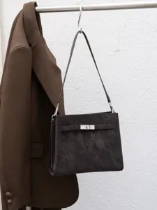 Vista detallada de un bolso de hombro retro oscuro con cierre elegante y chaqueta a juego.