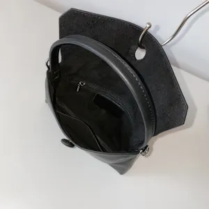 Black genuine leather handbag interior detail showing zipper pocket and smooth lining structure.