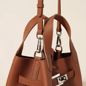 Gros plan de détail sur le sac à main en cuir marron texturé avec fermoir en métal.