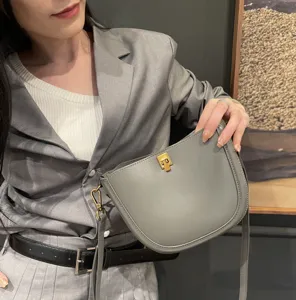 Detail view showing a chic grey leather saddle bag featuring a gold-tone lock closure.