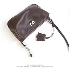 Brown leather shoulder bag detail showing metallic turn lock and zipper closure hardware.