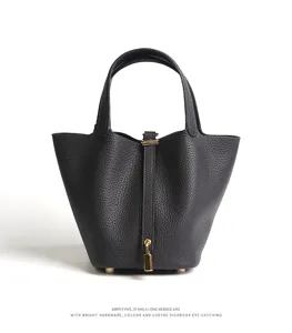 Close-up detail of genuine leather black bucket handbag with golden metallic lock hardware.