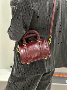 Close-up detail of the retro burgundy leather Boston handbag showing premium texture and hardware.