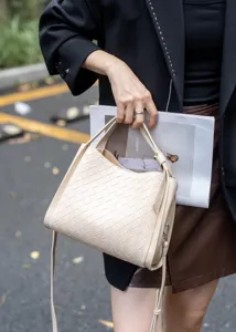 Detailed view of beige leather woven handbag with top handle and adjustable strap chic style