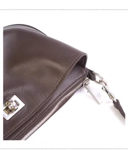 Brown leather shoulder bag detailed shot, minimalist design with metal zipper and lock.