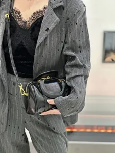 Close-up detail shot showing the black glossy leather Boston bag with gold hardware.