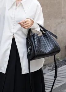 Detailed view of black woven leather shoulder crossbody bag with premium texture and metal hardware.