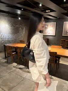 Black leather shoulder underarm bag with metal lock, stylish mini baguette handbag.