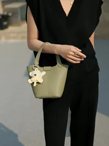 Stylish genuine leather bucket bag for women, elegant daily handbag with cute pendant design.