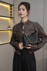 Detailed view of the black quilted leather underarm bag with elegant gold chain strap in use.