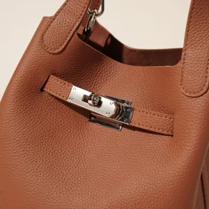 Gros plan sur les accessoires du sac seau en cuir marron, texture graine, detail elegant.