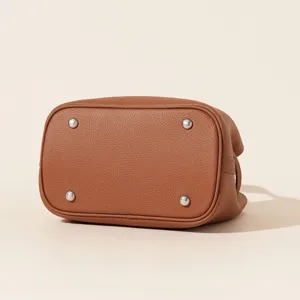 Détail du fond de sac-seau en cuir véritable marron avec pieds de protection en métal fin.