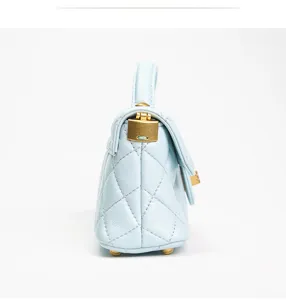 Detailed side view of light blue quilted mini handbag with elegant gold hardware and top handle.