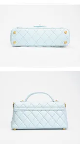 Detail view of light blue quilted leather top handle bag showing bottom metal feet design.