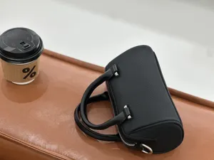 Detailed shot of a black leather boston bag showing fine texture, cylindrical shape, and hardware.