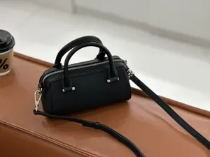Black leather Boston mini handbag detail shot, featuring dual top handles and a shoulder strap.