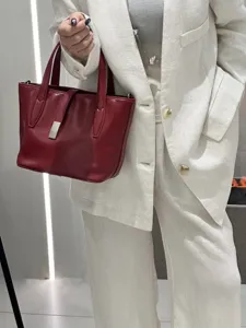 Red leather tote bag detail showing premium genuine cowhide texture and elegant metal hardware closure.