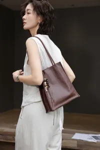Brown genuine leather tote bag featuring wooden bead charm, stylish shoulder bag for women.
