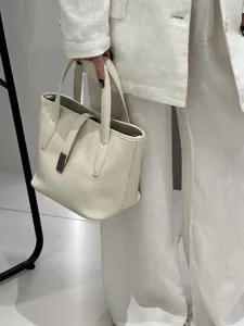 Minimalist cream leather tote bag detail featuring elegant metal clasp and premium finish.
