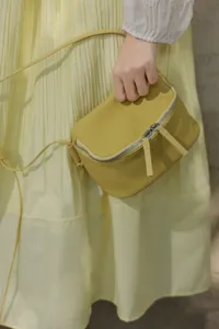 Detail shot of a minimalist genuine leather crossbody bag, mini lunch box style, yellow.