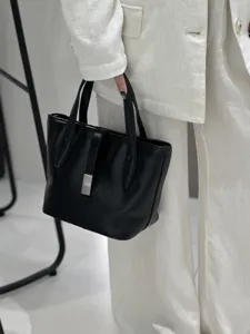 Close-up view of the elegant black leather bucket bag, featuring metal clasp and textured finish.