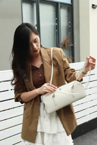 Genuine leather bowling bag detail shot, minimalist shoulder crossbody underarm bag style.