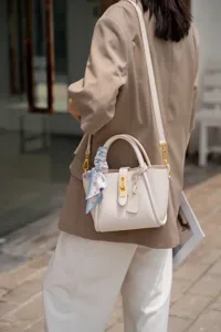 Elegante borsa a secchiello in pelle da donna con manico, serratura in metallo e foulard.