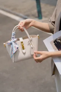 Vista dettaglio della elegante borsa secchiello in vera pelle, borsa beige con foulard.