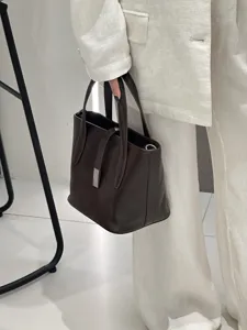 Dark brown genuine leather tote bag detail, featuring top handles and sleek metal closure.