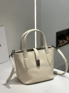 Elegant cream leather bucket bag with double top handles and chic metal clasp for daily women.