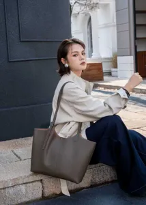 Detail view of the genuine leather tote bag worn by a model in an outdoor street setting.