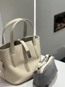 Detailed view of the elegant beige leather tote bag and striped pouch, showcasing premium texture.