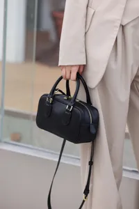Women black leather Boston bag detail view, classic pillow handbag with shoulder strap.