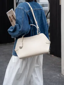 Detail view of off-white leather shoulder bag with metal hardware and handle.